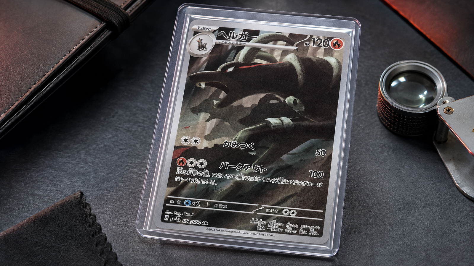 Japanese Houndoom Pokémon card protected in a sleeve and semi-rigid holder on a dark inspection surface